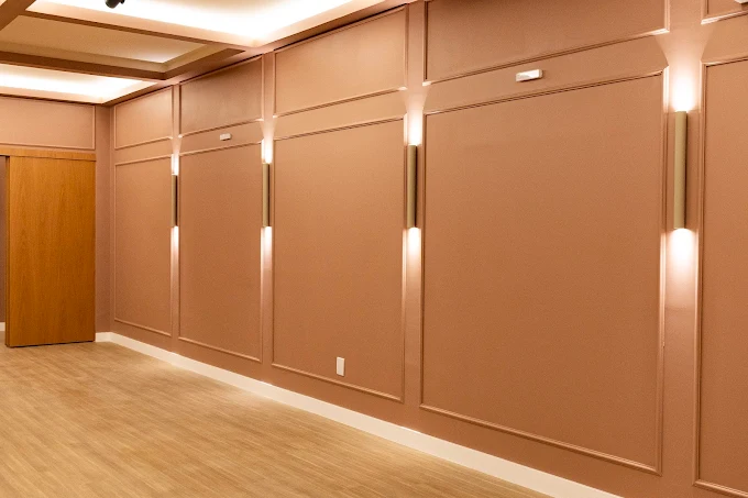 Corredor interno com painéis rosé e luminárias